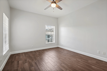 A room with a ceiling fan and wooden flooring.